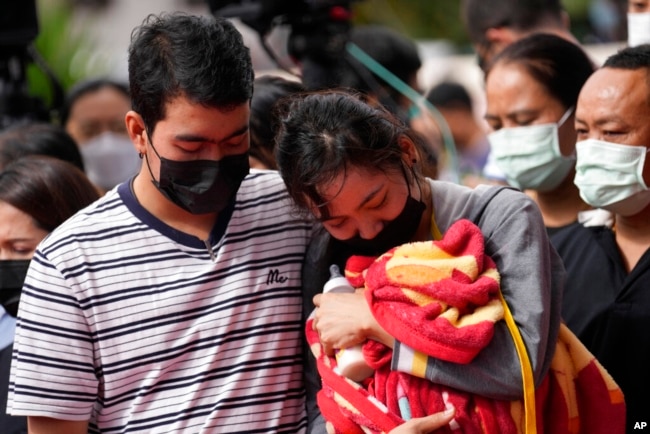 A family of a victim mourns as they bring a blanket and a baby bottle during a ceremony for those killed in the attack on the Young Children's Development Center in Uthai Sawan, Thailand, Oct. 7, 2022.
