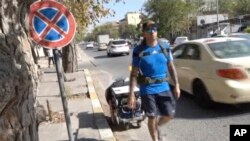 In this frame grab from video, 41-year-old Santiago Sanchez, a Spanish man who was documenting his travel by foot from Madrid to Doha for the 2022 FIFA World Cup, carries a suitcase in a wheeled cart, in Sulaymaniyah, Iraq, Sept. 28, 2022.