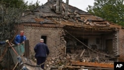 People work to remove debris from a damaged house after an overnight Russian shelling, in Sloviansk, Donetsk region, Ukraine, Monday, Oct. 10, 2022.