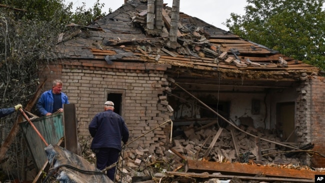 Pessoas trabalham para remover detritos de uma casa danificada após um bombardeio russo durante a noite, em Sloviansk, região de Donetsk, Ucrânia, segunda-feira, 10 de outubro de 2022.
