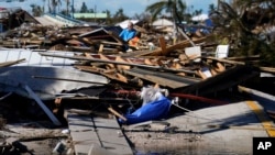 Sejumlah petugas dari Moya Group memeriksa kerusakan sebuah jembatan yang menghubungkan akses menuju Pulau Pine di wilayah Matlacha, Florida, pada 2 Oktober 2022. Jembatan tersebut rusak setelah Badai Ian menerjang wilayah Florida. (Foto: AP/Gerald Herbert)