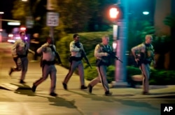 FILE - Police run toward the scene of a shooting near the Mandalay Bay resort and casino on the Las Vegas Strip in Las Vegas on Oct. 1, 2017. (AP Photo/John Locher, File)