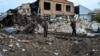 People stand by a crater left near a railway yard of the freight railway station in Kharkiv, which was partially destroyed by a missile strike, Sept. 28, 2022.