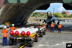 台灣軍隊士兵站在F16V戰機前，準備進行裝載美制AGM-84魚叉反艦導彈及AIM-120和AIM-9空空導彈的訓練。（2022年9月16日）