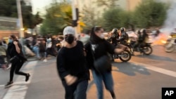 FILE - In this Sept. 19, 2022, photo taken by an individual not employed by the Associated Press and obtained by the AP outside Iran, women run away from anti-riot police during an anti-government protest in downtown Tehran.