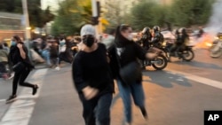 FILE - In this Sept. 19, 2022, photo taken by an individual not employed by the Associated Press and obtained by the AP outside Iran, women run away from anti-riot police during an anti-government protest in Tehran.