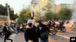 En esta foto del 19 de septiembre de 2022 tomada por una persona durante una protesta en Teherán, se observan presuntos Basijis en motocicletas tratando de disolver la manifestación.