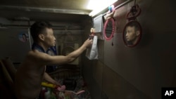 FILE - A man tidies up the bed in his tiny apartment in Hong Kong.