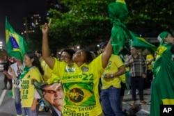 Supporters of Brazilian President Jair Bolsonaro, who is running for another term, celebrate partial results after general election polls closed outside his family home in Rio de Janeiro, Brazil, Sunday, Oct. 2, 2022. (AP Photo/Bruna Prado)