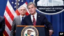 FBI Director Christopher Wray, joined at left by Attorney General Merrick Garland, speaks to reporters as they announce charges against two men suspected of being Chinese intelligence officers for attempting to obstruct a U.S. criminal investigation and p