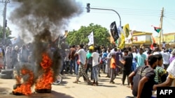 Demonstrators march past burning tires in a protest in the area of Bashdar in the south of Sudan's capital, Khartoum, Oct. 25, 2022, on the first anniversary of the military's arrest of the civilian administration that shared power after the 2019 overthrow of longtime autocrat Omar al-Bashir.