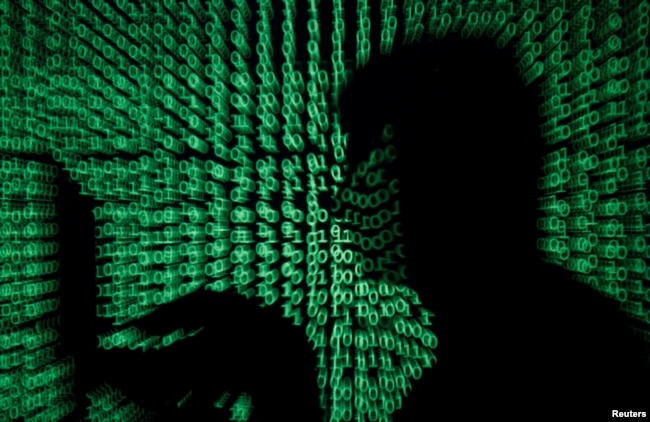 FILE PHOTO: A man holds a laptop computer as cyber code is projected on him in this illustration picture taken on May 13, 2017. (REUTERS/Kacper Pempel)