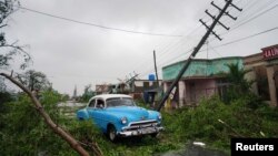 Un automóvil antiguo pasa entre los escombros causados por el huracán Ian en Pinar del Río, Cuba, el 27 de septiembre de 2022.