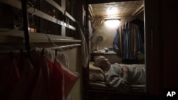 FILE - In this March 28, 2017 photo, a retired waiter sleeps in his 'coffin home' in Hong Kong.