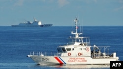 FILE - Kapal penjaga pantai Filipina (kanan) berlayar melewati kapal penjaga pantai China selama latihan pencarian dan penyelamatan bersama antara penjaga pantai Filipina dan AS di dekat Beting Scarborough di Laut Cina Selatan, 14 Mei 2019.