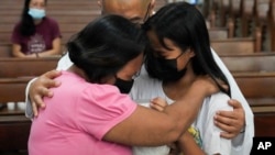 FILE - Catholic priest Flaviano "Flavie" Villanueva comforts relatives as they receive the urn containing the remains of victims of alleged extrajudicial killings at a church in Quezon city, Philippines, Wednesday, Sept. 28, 2022.