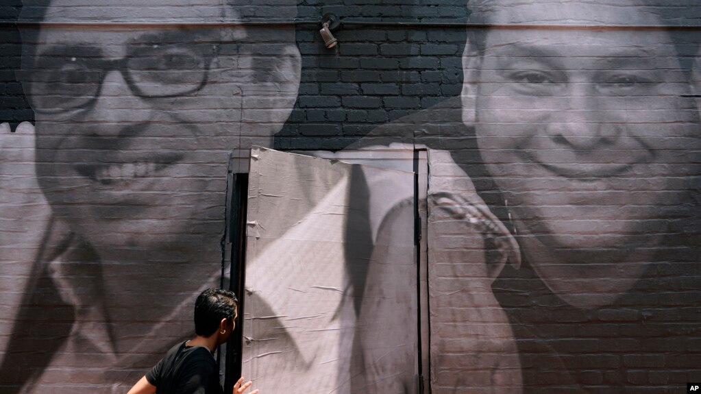 FILE - A woman steps through a door covered by a mural depicting American hostages and wrongful detainees held abroad, July 20, 2022, in Washington. At left is Siamak Namazi, who has been in captivity in Iran since 2015. 