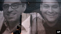 FILE - A woman steps through a door covered by a mural depicting American hostages and wrongful detainees held abroad, July 20, 2022, in Washington. At left is Siamak Namazi, who has been in captivity in Iran since 2015. 