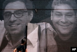 FILE - A woman steps through a door covered by a mural depicting American hostages and wrongful detainees held abroad, July 20, 2022, in Washington. At left is Siamak Namazi, who has been in captivity in Iran since 2015.