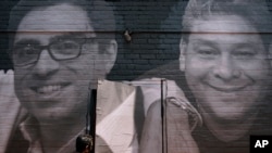 FILE - A woman steps through a door covered by a mural depicting American hostages and wrongful detainees held abroad, July 20, 2022, in Washington. At left is Siamak Namazi, who has been in captivity in Iran since 2015. 