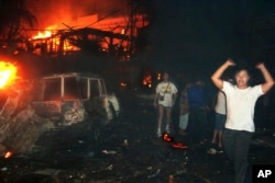 FILE - Residents and foreign tourists evacuate the scene of a bomb blast in Kuta, Bali, Indonesia, on Oct. 13, 2002. (AP Photo/Radar Bali, File)