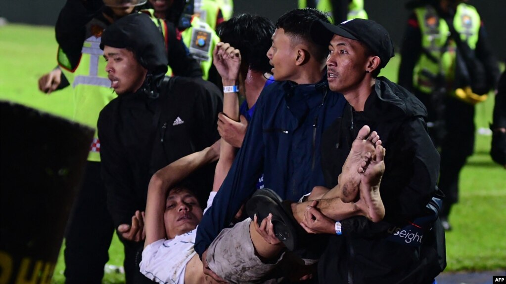 在这张2022年10月1日的照片中，在东爪哇马郎市的坎朱鲁汗体育场，阿雷马足球俱乐部和帕尔斯巴亚的足球比赛结束后发生踩踏事件，一群人抬着一名受伤的男子。