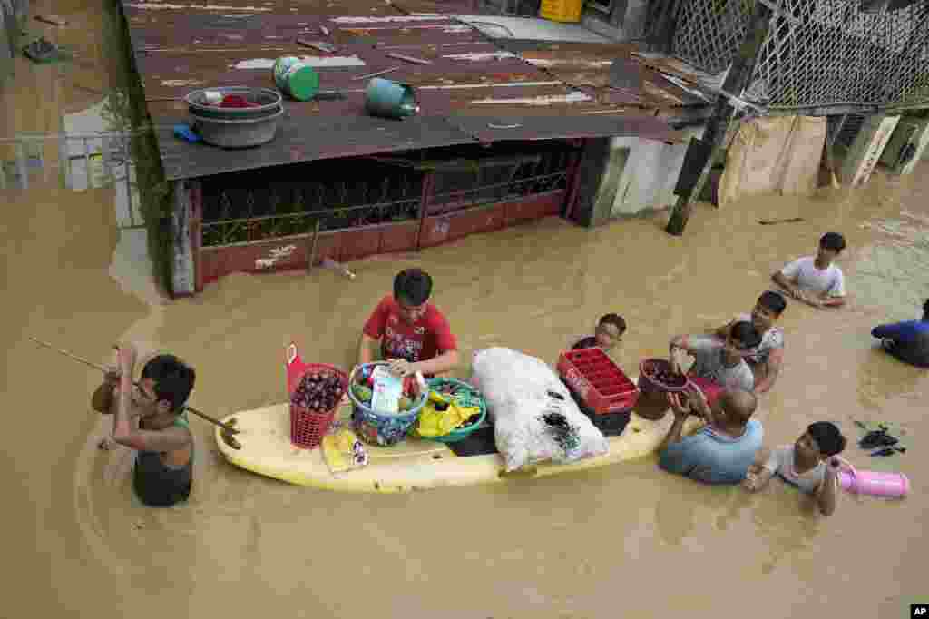 Residents give away onions and other foods along a road flooded by Typhoon Noru, in San Miguel town, Bulacan province, Philippines, Sept. 26, 2022.