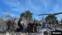 FILE - Distressed local residents sit at a site of a residential area heavily damaged by a Russian missile strike in Zaporizhzhia, Ukraine, Oct. 9, 2022.
