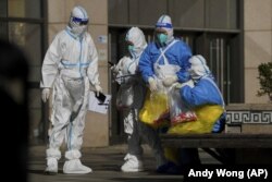 Medical workers carry bags of COVID test samples taken from the people who work at a shopping mall on Oct. 17, 2022. (AP/Andy Wong)