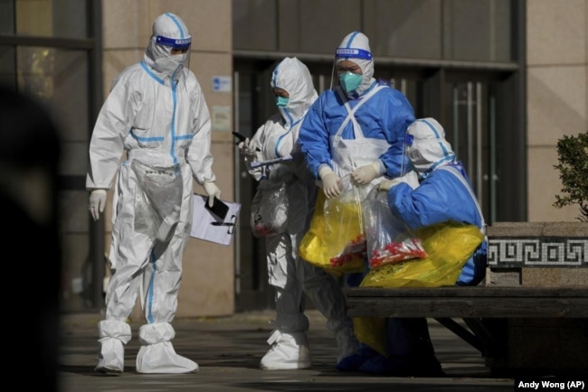 Medical workers carry bags of COVID test samples taken from the people who work at a shopping mall on Oct. 17, 2022. (AP/Andy Wong)