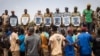 Mourners hold photos of some of the 27 soldiers killed as they escorted 207 vehicles in a convoy during their funeral at the General Sangoule Lamizana military camp in Ouagadougou, Burkina Faso, Oct. 8, 2022.