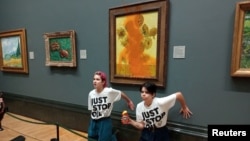 Activists of "Just Stop Oil" glue their hands to the wall after throwing soup at a van Gogh's "Sunflowers" painting at the National Gallery in London, Britain, Oct. 14, 2022. (Just Stop Oil/Handout via Reuters)