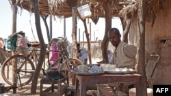 FILE: Abdalla Ibrahim, the Sudanese owner of a coffee shop and father of seven, looks on as he sits behind a pot on a fire in the village of Gosla in Sudan's eastern state of Kassala. Taken Sept.27, 2022.