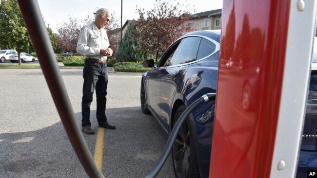 FILE - Bob Palrud of Spokane, Wash. speaks with a fellow electric vehicle owner who is charging up at a station along Interstate 90, on Wednesday Sept. 14, 2022, in Billings, Montana. (AP Photo/Matthew Brown)