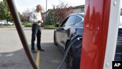 Bob Palrud of Spokane, Wash. speaks with a fellow electric vehicle owner who is charging up at a station along Interstate 90, on Wednesday Sept. 14, 2022, in Billings, Mont. Palrud says distances between EV charging stations are always on his mind during 