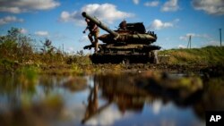 A journalist takes photographs atop of a destroyed Russian tank in Chystovodivka village, Ukraine, Oct. 6, 2022.