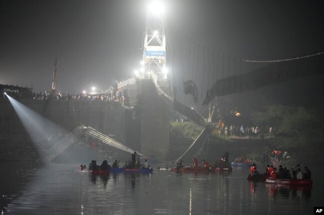 Rescuers on boats search in the Machchu river next to a cable suspension bridge that collapsed in Morbi town of western state Gujarat, India, Monday, Oct. 31, 2022. (AP Photo/Ajit Solanki)