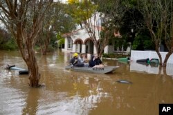 FILE - Orang-orang mendayung melalui jalan yang banjir di Windsor di pinggiran Sydney, Australia, 5 Juli 2022. (AP/Mark Baker, File)