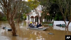 Sejumlah warga menaiki perahu mengarungi jalanan yang banjir di Windsor, pinggiran Kota Sydney, Australia, pada 5 Juli 2022. (Foto: AP/Mark Baker)