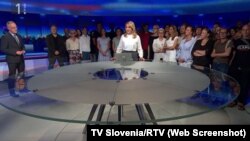 Journalists at Slovenia public broadcaster RTV gather during a live broadcast to show support for colleagues who had been reassigned after an anchor introduced a segment by saying it was being broadcast under the instruction of the chief news editor. (Screenshot TV Slovenia/RTV)