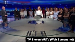 Journalists at Slovenia public broadcaster RTV gather during a live broadcast to show support for colleagues who had been reassigned after an anchor introduced a segment by saying it was being broadcast under the instruction of the chief news editor. (Screenshot TV Slovenia/RTV) 