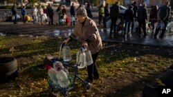 Catherine, de 75 años, empuja su andador cargado con botellas de plástico después de volver a llenarlas en un tanque, en el centro de Mykolaiv, Ucrania, el 24 de octubre de 2022