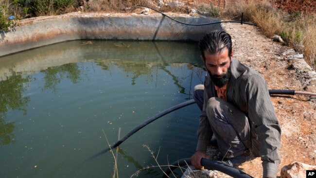 Nazih Sabra sets a tube to pump water from an artificial pond at Harf Beit Hasna village in Dinnieh province, north Lebanon, Sept. 7, 2022.