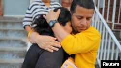 FILE - A woman from El Salvador is embraced by a family friend before leaving Vive La Casa shelter by taxi with her daughters to file a refugee claim at the Canadian border, in Buffalo, N.Y., July 5, 2017.