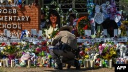 FILE - A police officer is seen in front of a makeshift memorial at Robb Elementary School in Uvalde, Texas, May 29, 2022.