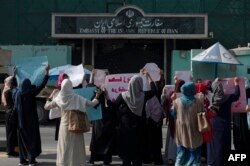 Afghan women hold placards as they take part in a protest in front of the Iranian embassy in Kabul, Sept. 29, 2022.