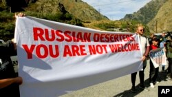 FILE - Activists hold an anti-Russian banner during an action organized by political party Droa near the border crossing at Verkhny Lars between Georgia and Russia in Georgia, Sept. 28, 2022. Some Georgians hace voiced concerns about the exodus of Russians into their country.