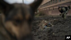 Policías ucranianos recogen fragmentos de un cráter para determinar el tipo de munición de un ataque ruso, el jueves 29 de septiembre de 2022, en Kramatorsk, Ucrania. (Foto AP/Leo Correa)