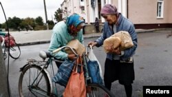 Raisa (R) and her relative receive humanitarian aid in the recently liberated town of Izium, in the Kharkiv region, Ukraine.