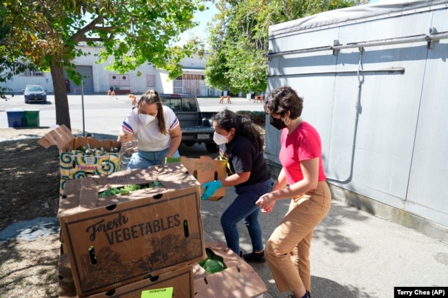 Patty Apple, right, helps load boxes at Food Shift, a nonprofit that collects food and gives it to the needy, Sept. 13, 2022. (AP Photo/Terry Chea)